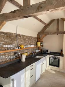 a kitchen with white cabinets and a stone wall at Beautiful countryside Byre conversion in Shrewsbury