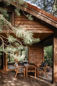 a wooden cabin with a table and chairs on a deck at Beržų namelis - Birch cabin in Kučiūnai