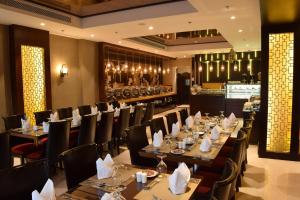 ein Restaurant mit Tischen und Stühlen und eine Bar in der Unterkunft Best Western Plus Fursan in Riad