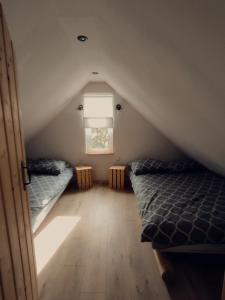 Schlafzimmer im Dachgeschoss mit 2 Betten und einem Fenster in der Unterkunft Domek letniskowy na Kaszubach z Balia ogrodowa in Gowidlino