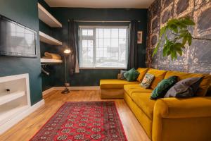 a living room with a yellow couch and a red rug at 3 bedroom home and garden in North Bristol in Bristol