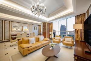 a living room with a couch and chairs and a chandelier at Dusit Hotel & Suites - Doha in Doha