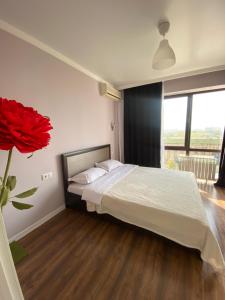 1 dormitorio con 1 cama y un jarrón de rosas rojas en Квартира в центре Алматы, en Almaty