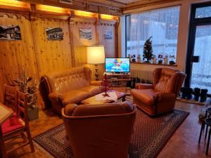 a living room with leather furniture and a television at Hotel Mont-Noble in Nax