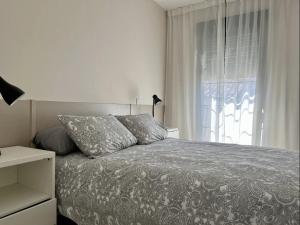 a white bedroom with a bed and a window at Apartamentos El Piquillo en Cadalso de los Vidrios in Cadalso de los Vidrios