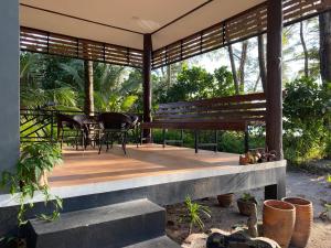 a porch with a bench and a table and chairs at Phayam Coconut Beach Resort in Ko Phayam