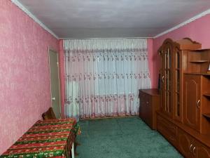 a bedroom with pink walls and a bed and a dresser at Гостевой коттедж 