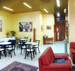 un restaurante con mesas y sillas y un sofá rojo en Hotel Ristorante Cordial, en Comiso