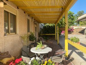 een patio met een tafel en stoelen onder een gele pergola bij O&B Hospitality - אירוח אלף בית in Dafna