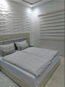 una camera bianca con un grande letto con cuscini di B&B DELUXE COMFORT a Fes