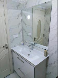 een witte badkamer met een wastafel en een spiegel bij B&B DELUXE COMFORT in Fès