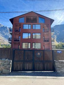 a house with a wooden gate and a fence at Kazbegi Apartments in Kazbegi