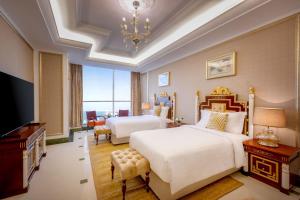 Dusit Hotel & Suites - Doha في الدوحة: غرفة نوم بسريرين وتلفزيون بشاشة مسطحة