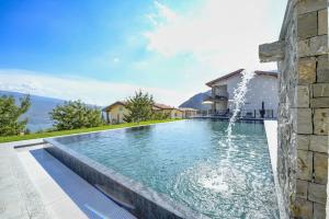 - une piscine avec une fontaine à côté d'une maison dans l'établissement Borgo Ermanno, à Tignale
