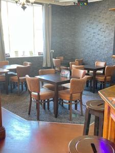 uma sala de jantar com mesas, cadeiras e janelas em The Swan Inn em Henwick