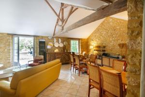 a kitchen and living room with a yellow couch and chairs at Le Clos Vallis in Sarlat-la-Canéda