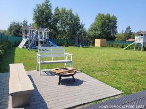 einen Spielplatz mit einer Bank und einem weißen Stuhl in der Unterkunft Domek letniskowy Młyn2 in Karwieńskie Błoto Pierwsze