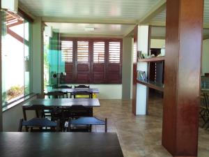 a dining room with tables and chairs and windows at Pousada Na Beira do Mar in Baía da Traição