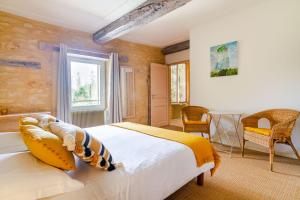 a bedroom with a bed and a chair and a window at Le Clos Vallis in Sarlat-la-Canéda