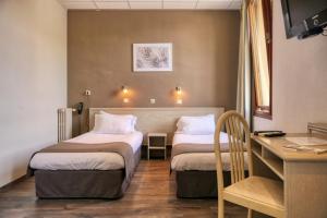 una camera d'albergo con 2 letti e una scrivania di CitHôtel Le Louvre a Orange