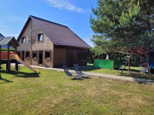 Casa con patio con sillas y parque infantil en Domek letniskowy Młyn, en Karwieńskie Błoto Pierwsze