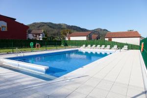 a large swimming pool with chairs in a yard at Cabañas La Senda de los elefantes Cabárceno in Cabarceno