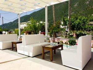 a patio with white chairs and tables and a mountain at Xenia Apartments in Vasiliki