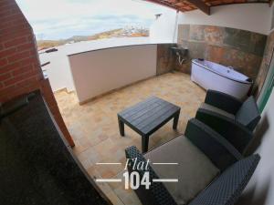 een kamer met een bad, een bank en een tafel bij TH Flats com Banheira de Hidromassagem in Governador Valadares