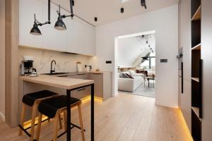 a kitchen with white cabinets and a table with stools at Wielka Odrzańska 317- RiverView in Szczecin