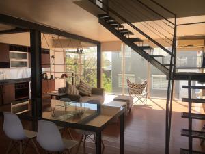 a living room with a glass table and a staircase at Rio Negro Loft in Viedma