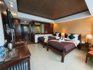 a hotel room with two beds and a television at Goldenbell Hotel Chiangmai in Chiang Mai