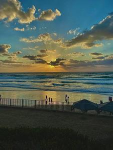 een groep mensen die bij zonsondergang op het strand lopen bij דירת סטודיו על הים בצפון תל אביב in Tel Aviv