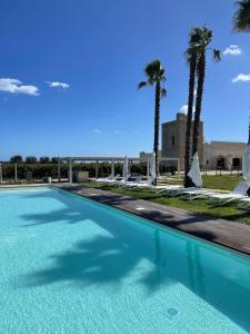 a large swimming pool with palm trees in the background at Masseria Torleanzi Wine Relais in San Pietro Vernotico