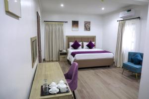 Habitación de hotel con cama y silla azul en Quest Boutique Hotel, en Gwarinpa