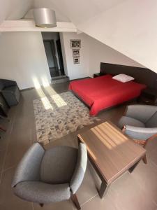 1 dormitorio con cama roja, mesa y sillas en Villa Natura, en Dolsk