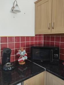 a kitchen with a black counter top with a microwave at Gîte l' Arbre de Vie in Les Essards