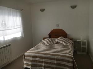1 dormitorio con 1 cama con manta a rayas y ventana en Rio Negro Loft en Viedma