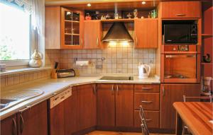 una cucina con armadi in legno, lavandino e forno a microonde di 3 Bedroom Gorgeous Home In Santoczno a Santoczno