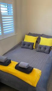 a bed with yellow and gray pillows on it at HenreeenOnWidewater in Lancing