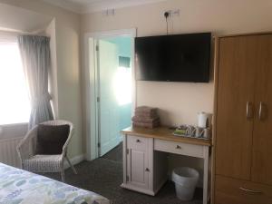 um quarto de hotel com uma secretária e uma televisão na parede em Fernlea Guest house em Weston-super-Mare