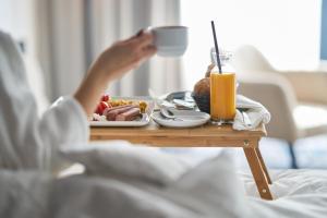 a person in bed with a tray of food on a table at Dusit Hotel & Suites - Doha in Doha