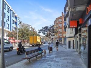 two people sitting on a bench on a city street at CozyCatalonia - Comfortable Apartment in Central Blanes in Blanes