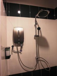 a shower in a bathroom with a dispenser on a wall at Supreme Hotel in Melaka
