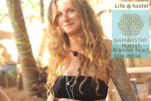 een vrouw met lang haar die naast een boom staat bij NamahStay Hostel, Cowork & Artist residency Arambol in Arambol