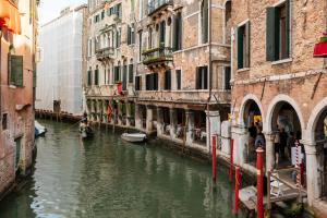Un canal entre dos edificios con barcos en el agua. en Hotel al Sotoportego, en Venecia