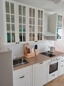- une cuisine avec des placards blancs et un évier dans l'établissement Boho apartament - studio, à Kołobrzeg