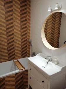 La salle de bains est pourvue d'un lavabo, d'un miroir et d'une baignoire. dans l'établissement Boho apartament - studio, à Kołobrzeg