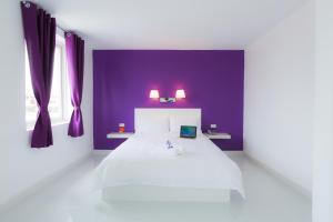 a bedroom with a white bed and purple walls at Hotel Zing Phnom Penh in Phnom Penh