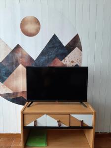 un televisor sentado en un stand frente a una pared en Appartement avec terrasse centre samoens, en Samoëns