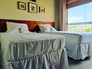 two beds with white sheets in a room with a window at Aruba Family Oasis 2BR Pool 3min Walk to Eagle Beach in Palm-Eagle Beach +62 photos